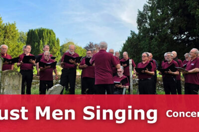 Around 20 men singing in a graveyard.
